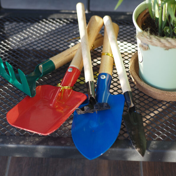Assorted gardening tools lie on a metal table near a potted plant.