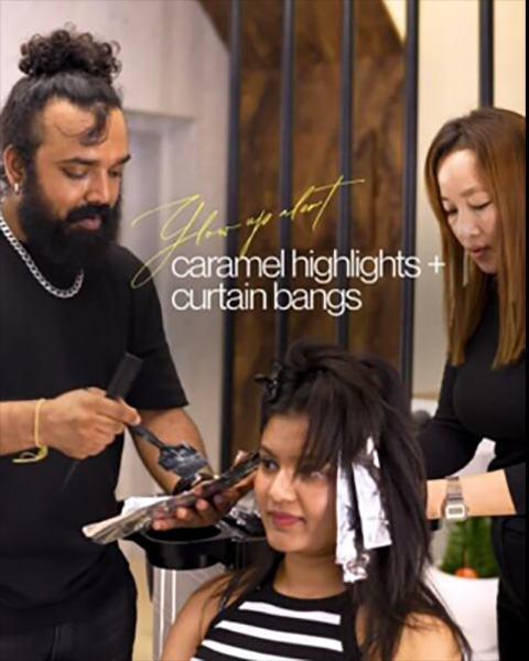 Professional Artysto stylists applying caramel highlights and styling curtain bangs for a client's hair transformation.
